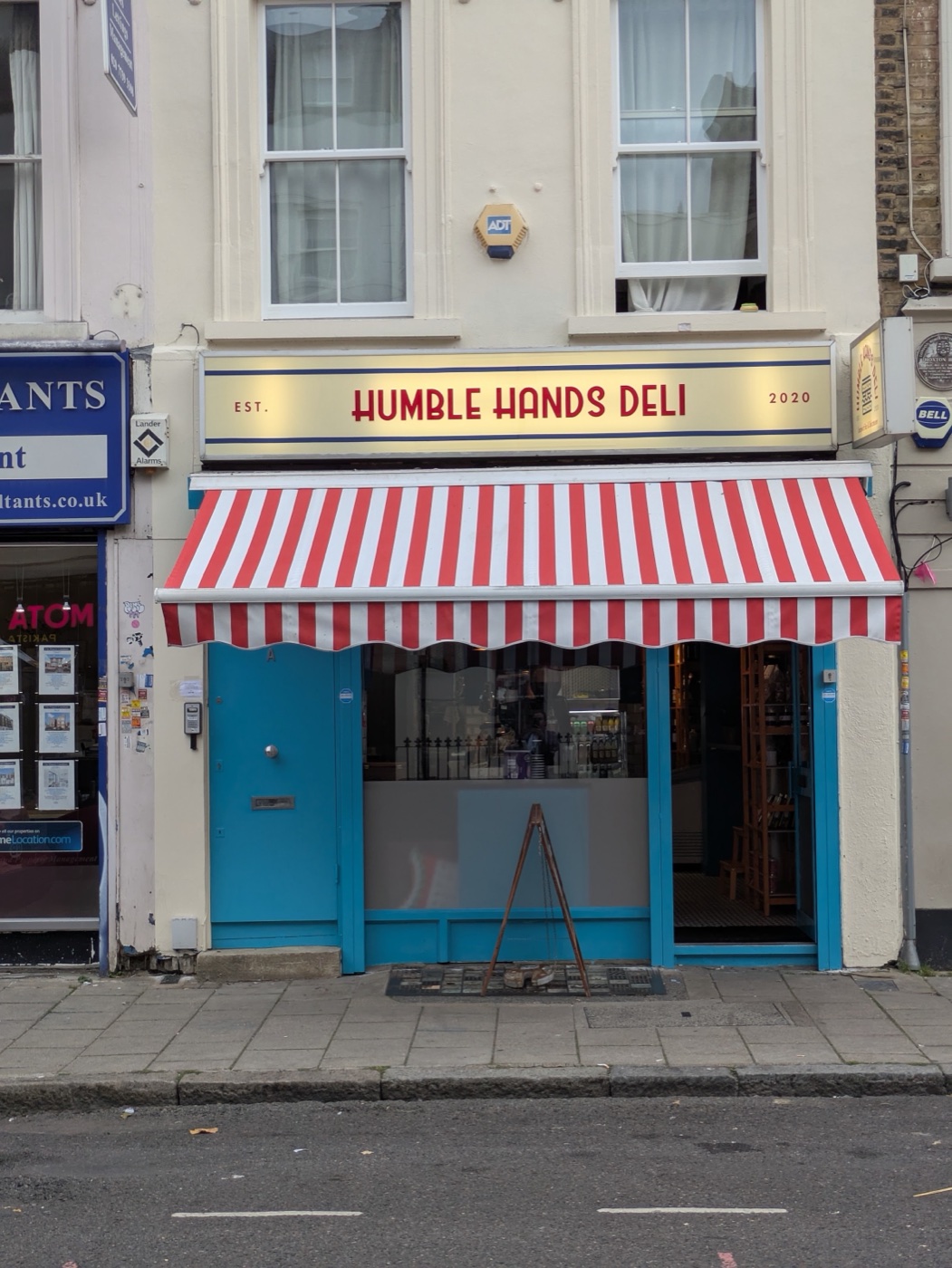 Humble Hands Deli's storefront on Hoxton Street, with its red-and-white awning and lit sign
